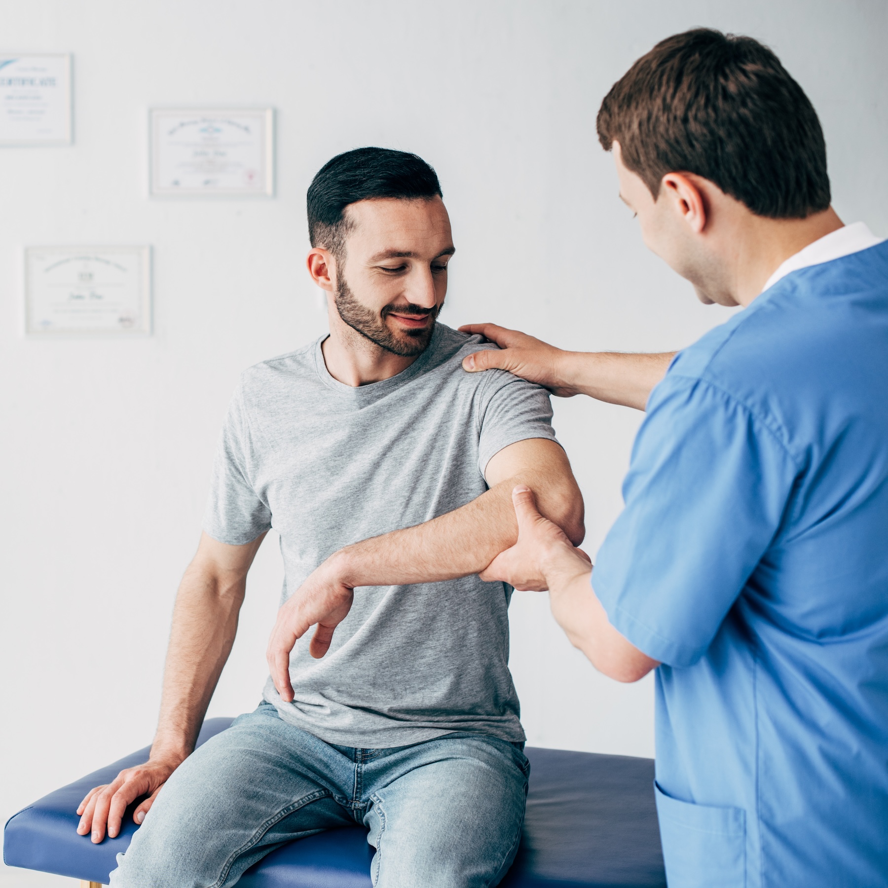 Chiropractor examining patient's shoulder at clinic